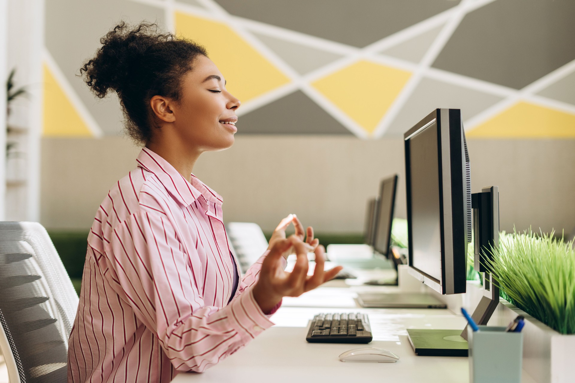 Office worker meditating at her desk for stress relief
